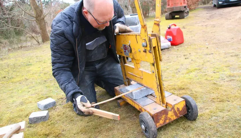 Man klipper marksten med en gul maskin.