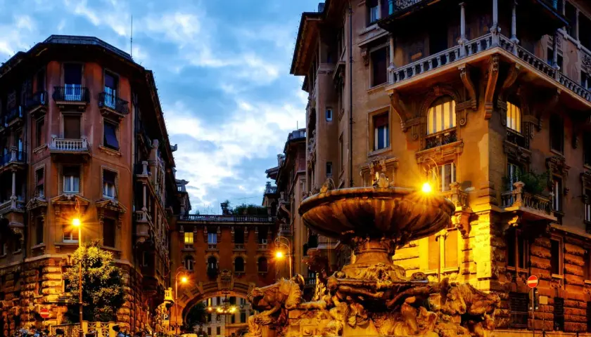Fontana e palazzi illuminati a Roma, quartiere Coppedè cosa vedere. Atmosfera magica al crepuscolo.