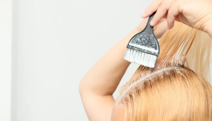 Persona se aplica tinta en el cabello, un proceso de tinta en casa para un cambio de look.