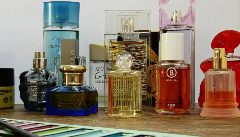 Różne flakoniki perfum i wód toaletowych na drewnianym blacie.