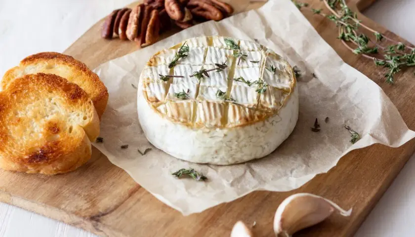 Pyszny, pieczony camembert z tymiankiem, podany z grzankami, orzechami pekan i czosnkiem. Idealny na przekąskę.