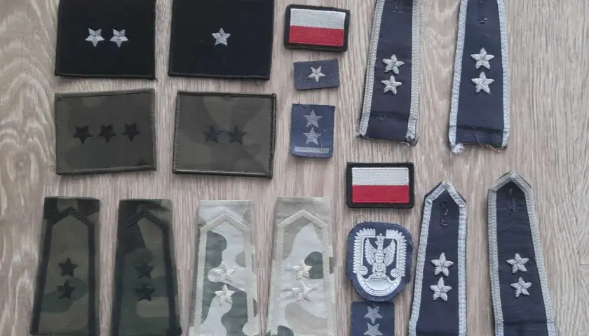 Różne stopnie wojskowe na pagonach i naszywkach, w tym polska flaga.