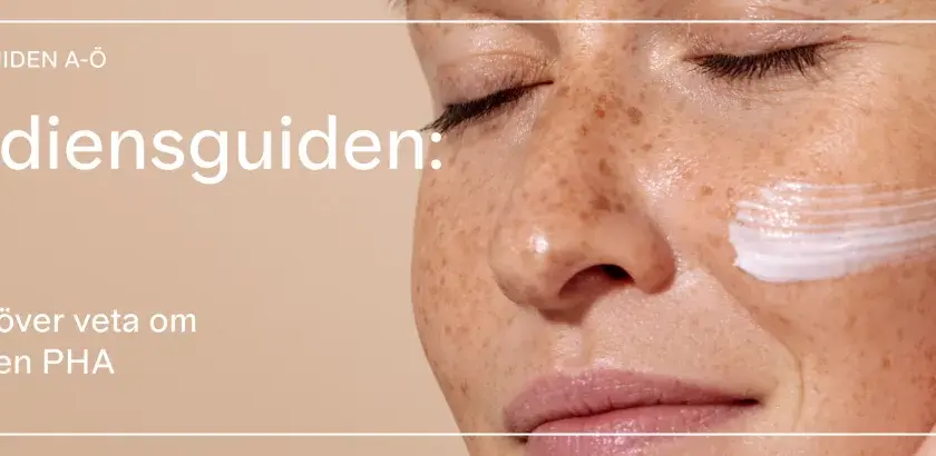 En närbild på en kvinna med fräknar som får en kräm applicerad på kinden. Texten lyder "Ingrediensguiden: PHA".