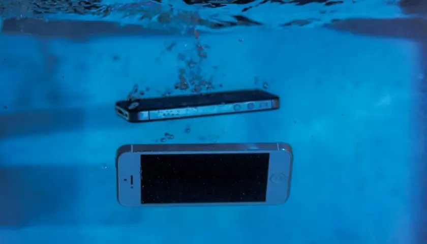 Dwa smartfony, jeden srebrny, drugi czarny, zanurzają się w wodzie. Ten wodoodporny smartfon przetrwa nawet takie zanurzenie.