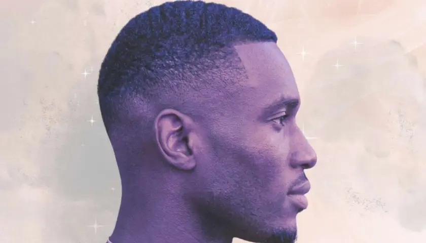 Perfil de hombre con un corte de pelo tuper fade, ondas definidas y barba corta.