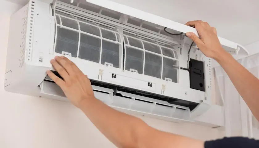 Man opens air conditioner to clean filters. Dirty filters can cause why the air conditioner freezes.