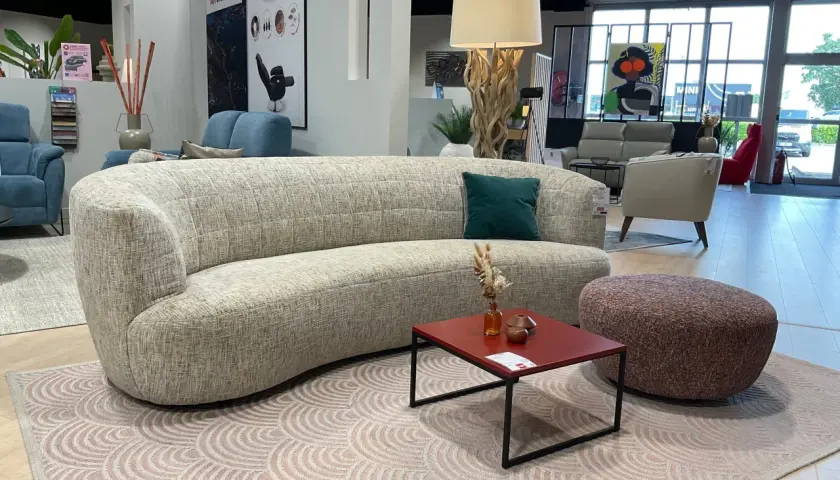 Un canapé courbé et un fauteuil rouge, illustrant la différence entre canapé et fauteuil, dans un showroom de meubles.