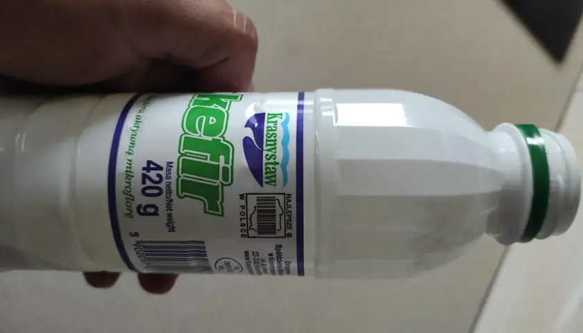 Butelka kefiru Krasnystaw 420g, z zieloną zakrętką, trzymana w dłoni.