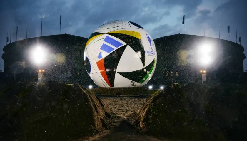 Gigantyczna piłka mistrzostw europy, symbol nadchodzącego turnieju, lśni w deszczu przed stadionem.
