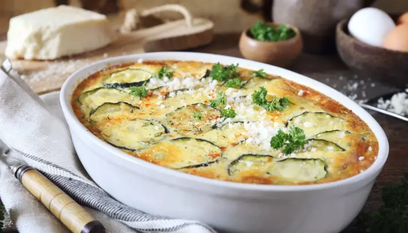 Szybka i prosta zapiekanka z cukinii, udekorowana natką pietruszki i parmezanem, gotowa do podania.