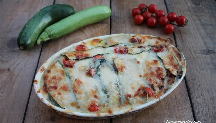 Parmigiana di zucchine non fritte, con pomodorini e formaggio filante, pronta per essere gustata.