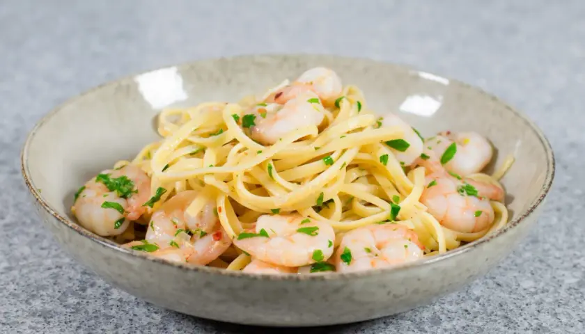 En skål med linguine och scampi, perfekt för ett snabbt scampi recept. Garnerad med färsk persilja.