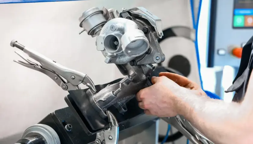 Mechanik pracuje nad turbosprężarką, przygotowując ją do czyszczenia n75. Urządzenie jest zamocowane w imadle.