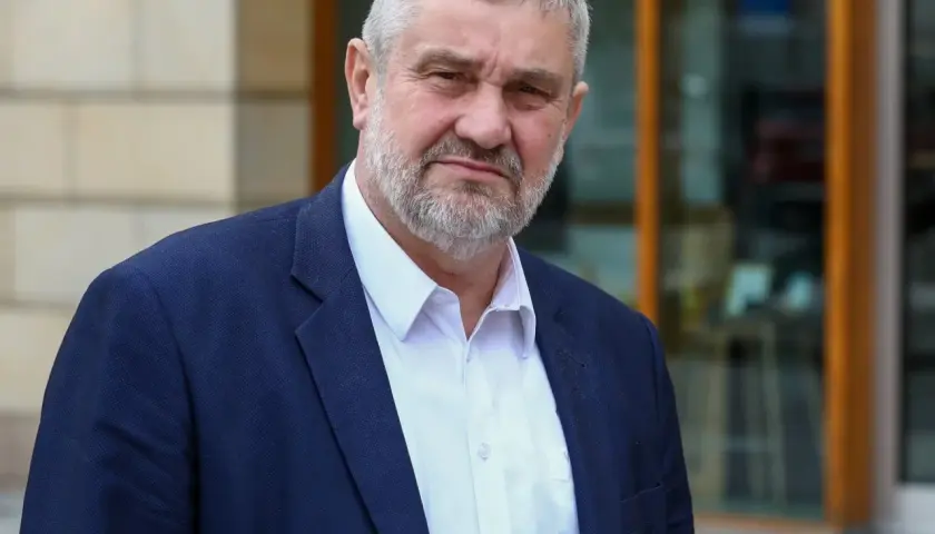 Mężczyzna z siwą brodą w granatowej marynarce i białej koszuli. Czy pozna prawdę o zarzutach prokuratorskich dla byłego ministra rolnictwa w 2025 roku?