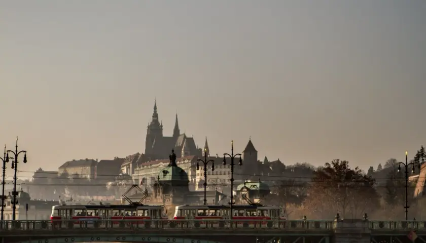 Most w Czechach z tramwajami na tle zamku.