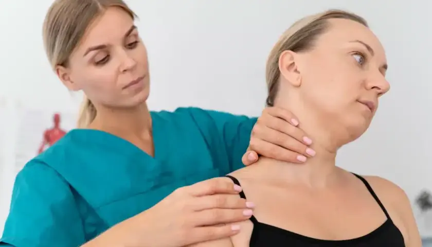 Fizjoterapeuta bada szyję pacjentki, oceniając potencjalne objawy chorobowe kręgosłupa szyjnego.