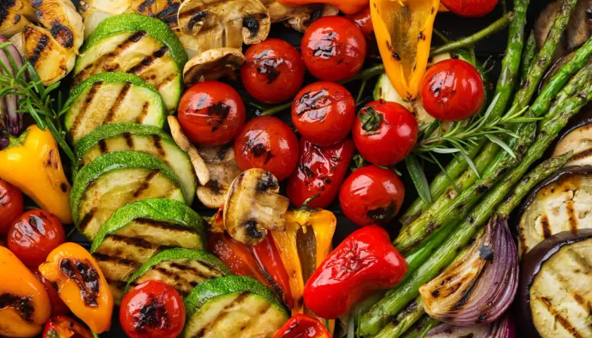 Un assortiment coloré de légumes grillés, parfait en accompagnement barbecue : courgettes, tomates cerises, poivrons, asperges, champignons, aubergines et oignons rouges.