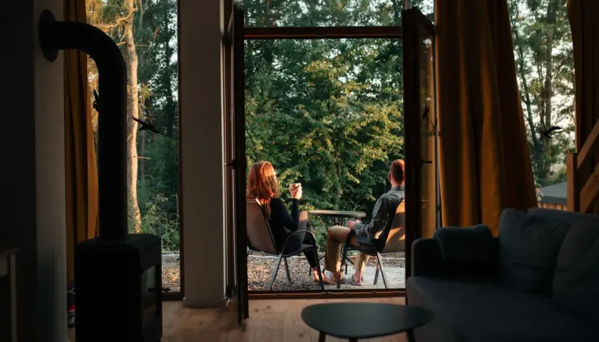 Para siedząca na zewnątrz przy kawie, z widokiem na las.