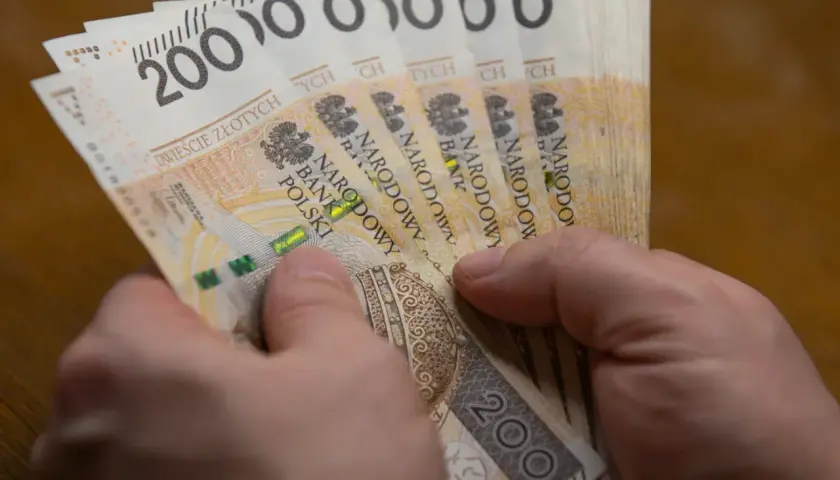 Dłonie trzymają stos banknotów po 200 zł. To hojna darowizna w pierwszej linii, która pomoże potrzebującym.