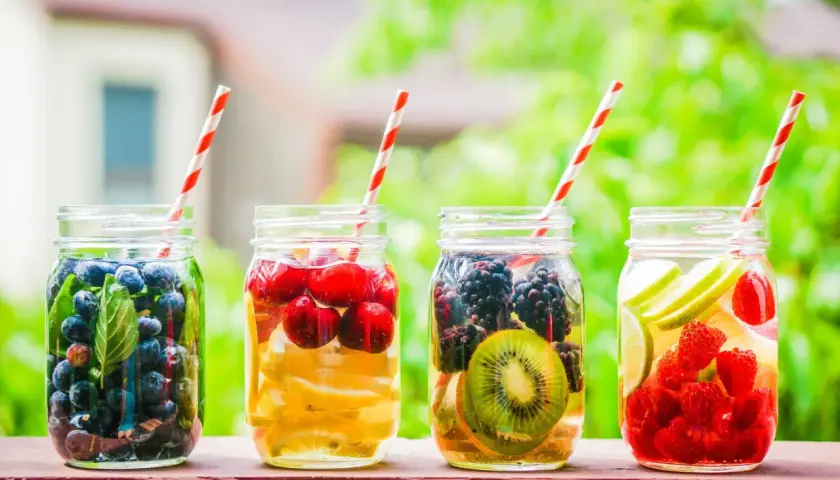 Quattro barattoli con acqua detox: mirtilli, ciliegie e limone, more e kiwi, lamponi e lime.