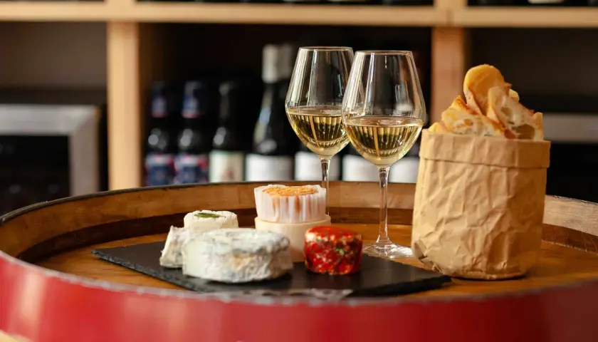 Dégustation de fromages et de pain frais avec deux verres de vin blanc, une scène parfaite pour un vin Paris.