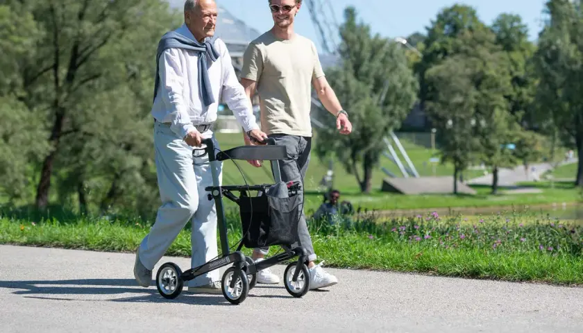 Ein älterer Mann geht mit einem Rollator spazieren, der ihm Halt gibt. Es gibt verschiedene Gehhilfen, die Mobilität im Alter unterstützen.