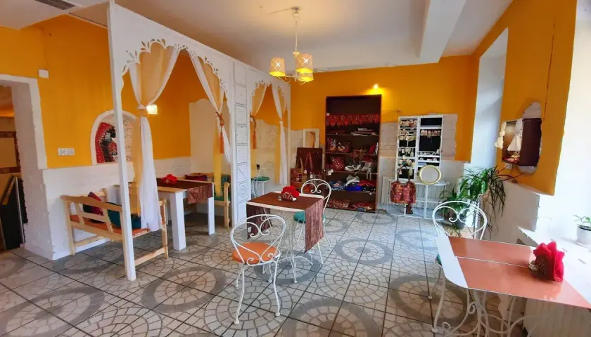 Wnętrze restauracji Samsara w Opolu, z żółtymi ścianami, białymi zdobieniami i stolikami. Idealne miejsce, by zapoznać się z ich menu.