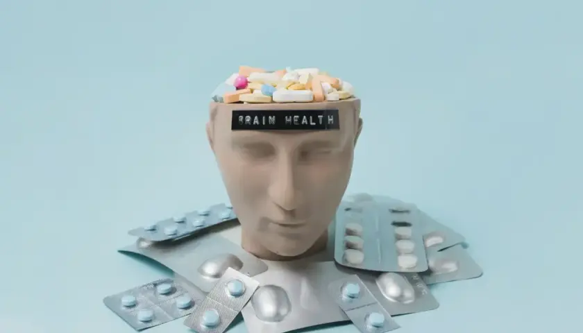 Testa di manichino piena di pillole, con la scritta "BRAIN HEALTH". Intorno, blister di psicofarmaci, suggerendo che il neurologo può prescrivere psicofarmaci.