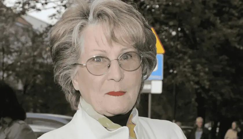 Irena Santor w okularach, z czerwoną szminką na ustach, w białej kurtce. Myśli o swoich dzieciach.