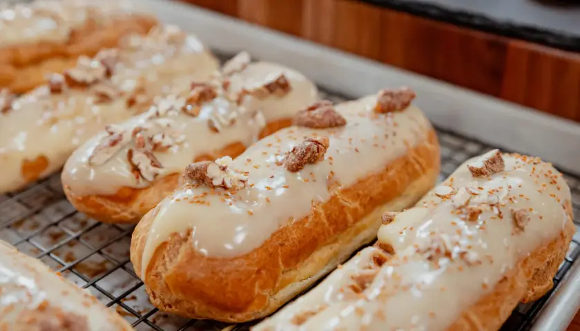 Éclairs dorés sur une grille, nappés d'un glacage sirop d'érable et parsemés de noix concassées. Un délice gourmand.