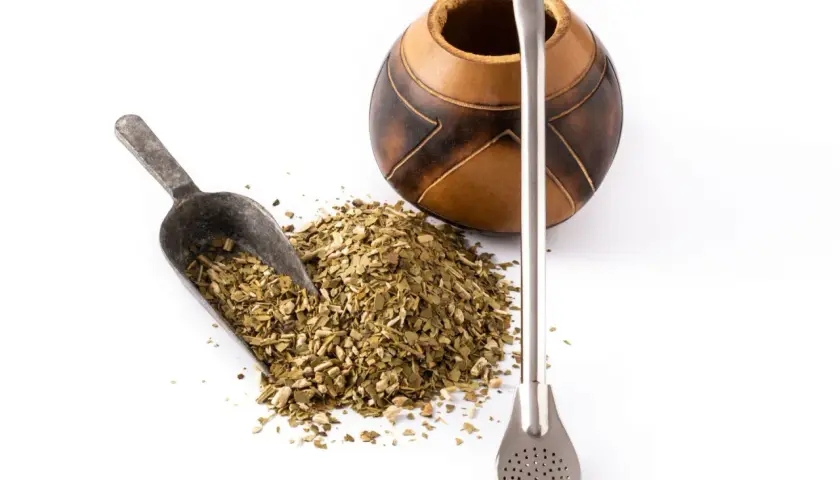 Naczynie z tykwy, metalowa bombilla i garść suszu do yerba mate. Różne rodzaje yerba mate czekają na zaparzenie.
