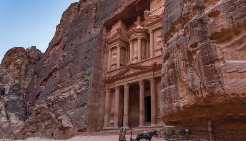 Skaliste klify Petry, Jordania, z wykutym w skale Skarbcem. Dwa wozy zaprzężone w osły czekają na turystów, marzących o jordania loty.