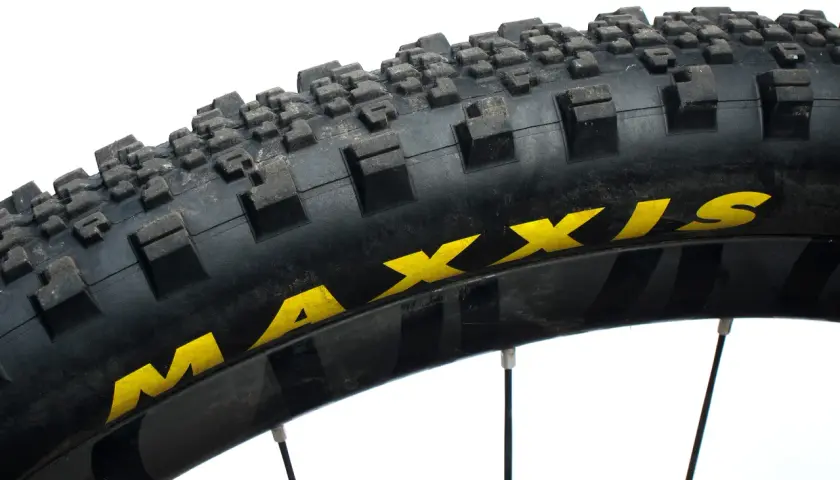 Close-up of a Maxxis Minion SS tire, showing its aggressive tread pattern and yellow branding. Ready for any trail.