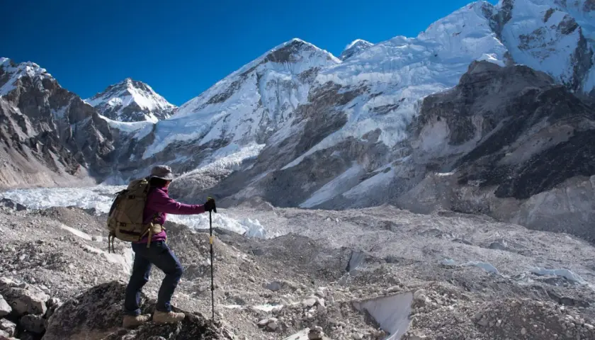 Turystka z plecakiem i kijkami trekkingowymi podziwia majestatyczne szczyty Himalajów w drodze do Everest Base Camp.