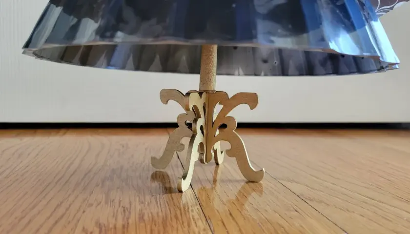 Base de un maniquí 3d de madera con un soporte ornamental, sosteniendo una falda de tela brillante.
