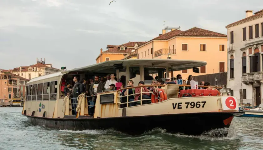 Un passager sur un vaporetto à Venise, naviguant sur les canaux bordés de bâtiments historiques.
