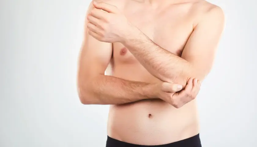 Mężczyzna trzyma się za łokieć, być może wykonuje test cozena.