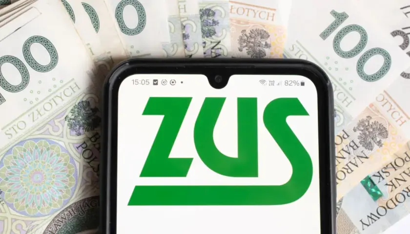 Telefon z logo ZUS na tle banknotów 100 zł. Dowiedz się, komu przysługuje dodatek pielęgnacyjny z ZUS.