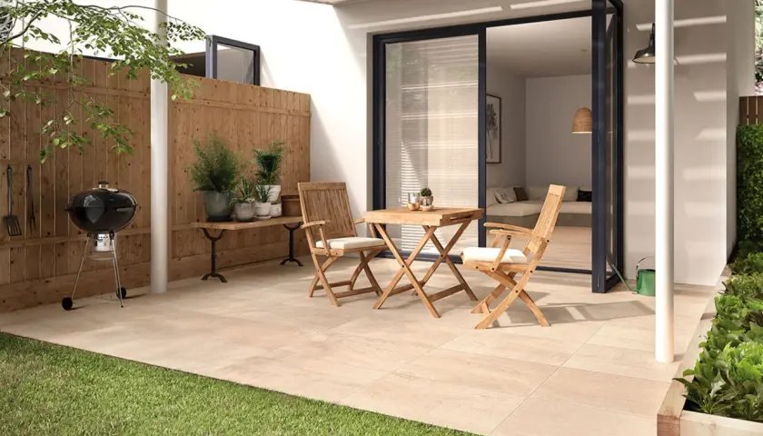 Ein moderner kleiner Garten am Reihenhaus mit Grill, Holztisch und Stühlen. Perfekt für entspannte Stunden.