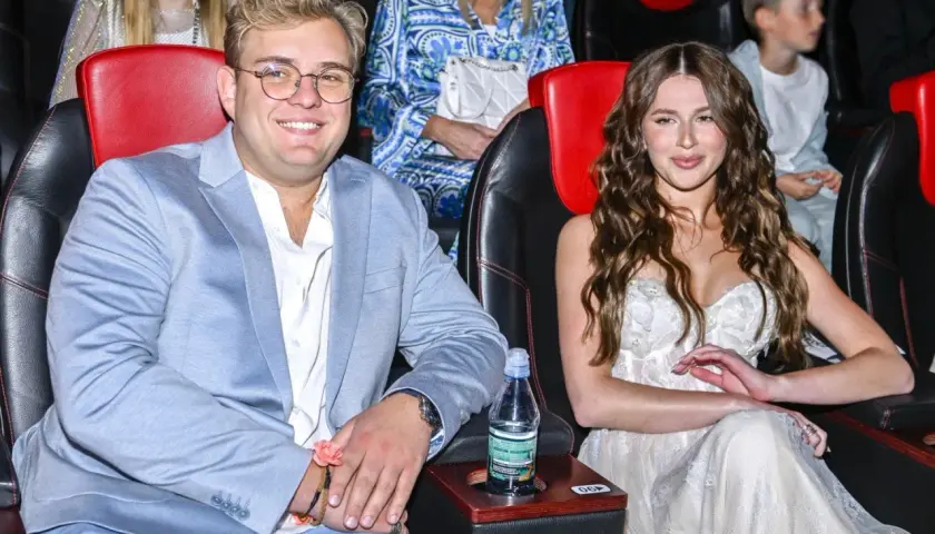 Roksana Węgiel i jej mąż, Kevin Mglej, siedzą w kinie. Ona w białej sukni, on w błękitnej marynarce.