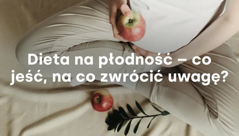 Kobieta w ciąży trzyma jabłko, obok leży drugie jabłko i gałązka.