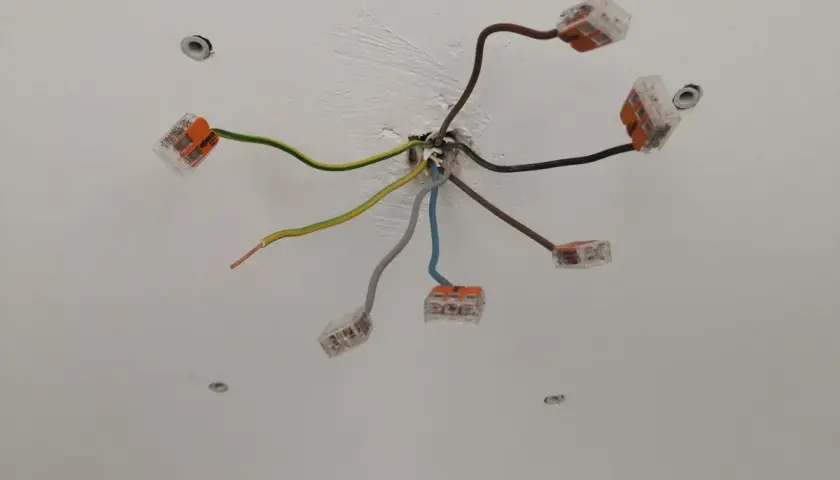 Sufit z instalacją elektryczną. Widać kilka przewodów, w tym jeden brązowy, połączonych złączkami.