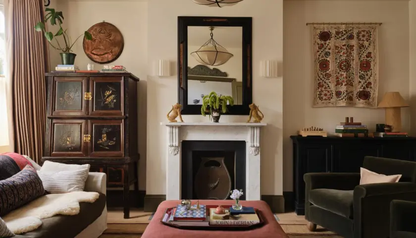 A living room with a fireplace, antique cabinet, and plush seating, showcasing a beautiful simplicity interior design.