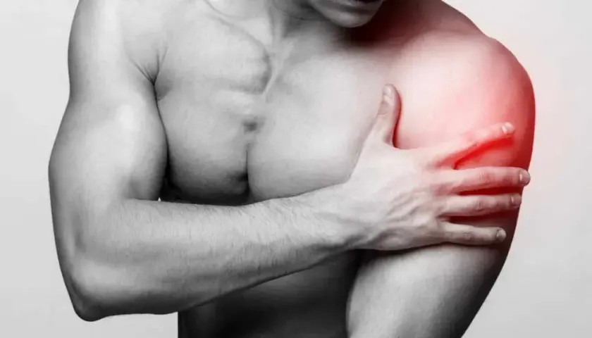 Un homme tient son épaule douloureuse, une longue portion de son bras est marquée en rouge pour indiquer la douleur.