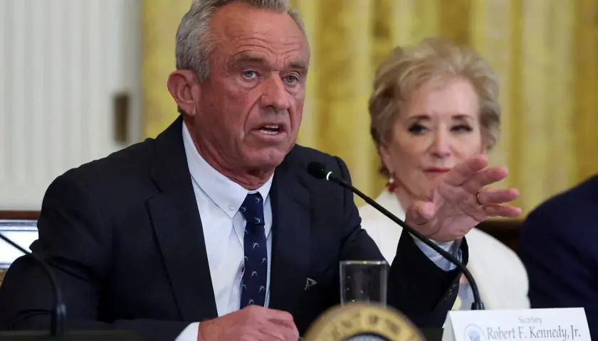 Robert F. Kennedy Jr. przemawia przy mikrofonie, obok siedzi kobieta.