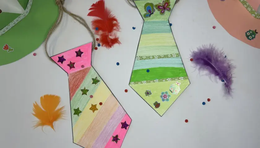 Bunte Krawatten basteln mit Federn und Stickern. Eine pinke und eine grüne Krawatte, dekoriert mit Sternen und Schmetterlingen.