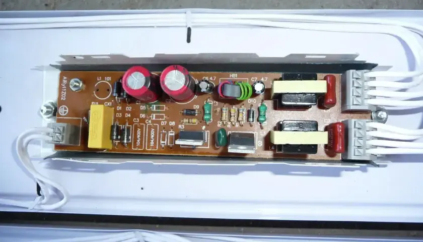 Elektroniczny statecznik z widocznymi kondensatorami, cewkami i innymi elementami na płytce drukowanej.