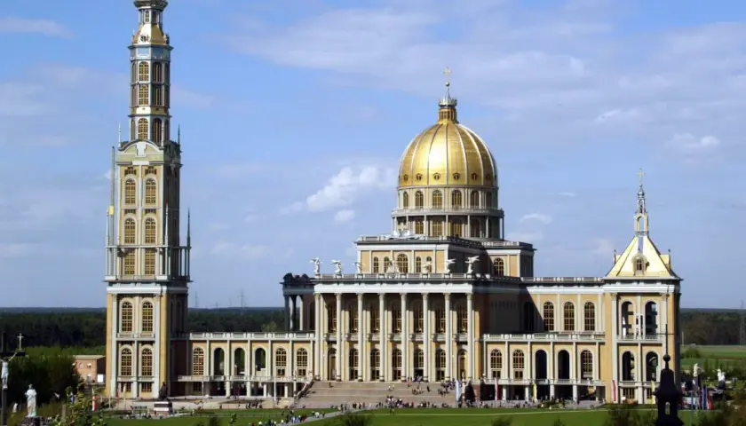Bazylika w Licheniu z wysoką wieżą i złotą kopułą na tle błękitnego nieba.