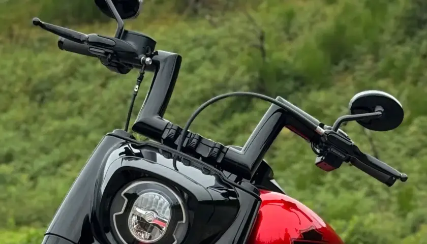 Manubrio drag bar Harley nero lucido, con specchietti e faro tondo.