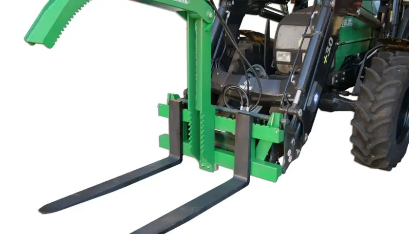 Grüner Greifer für Palettengabel, montiert an einem Traktor. Ideal zum sicheren Transport von Rundholz oder anderen sperrigen Lasten.